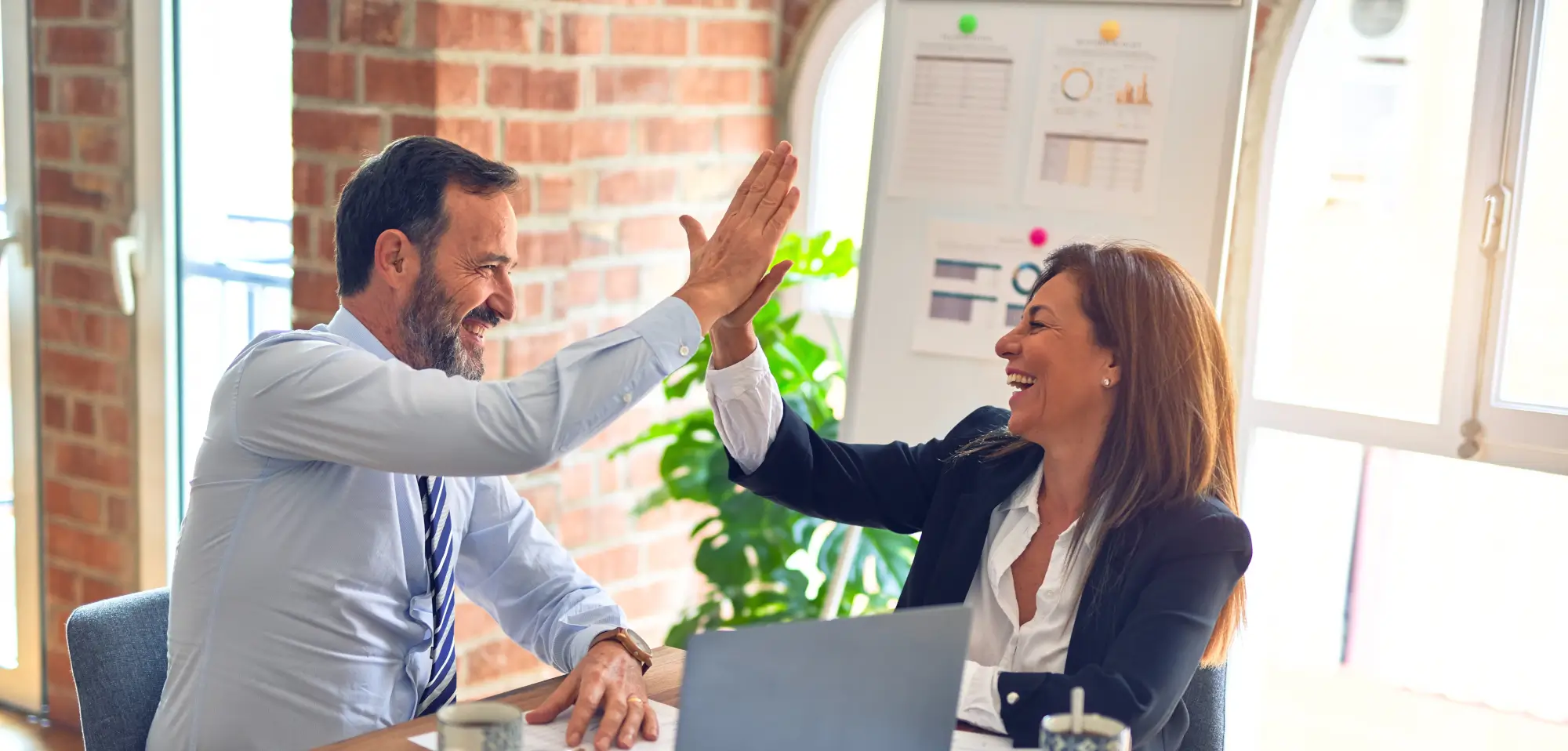 Woman high-fiving a man during a business meeting