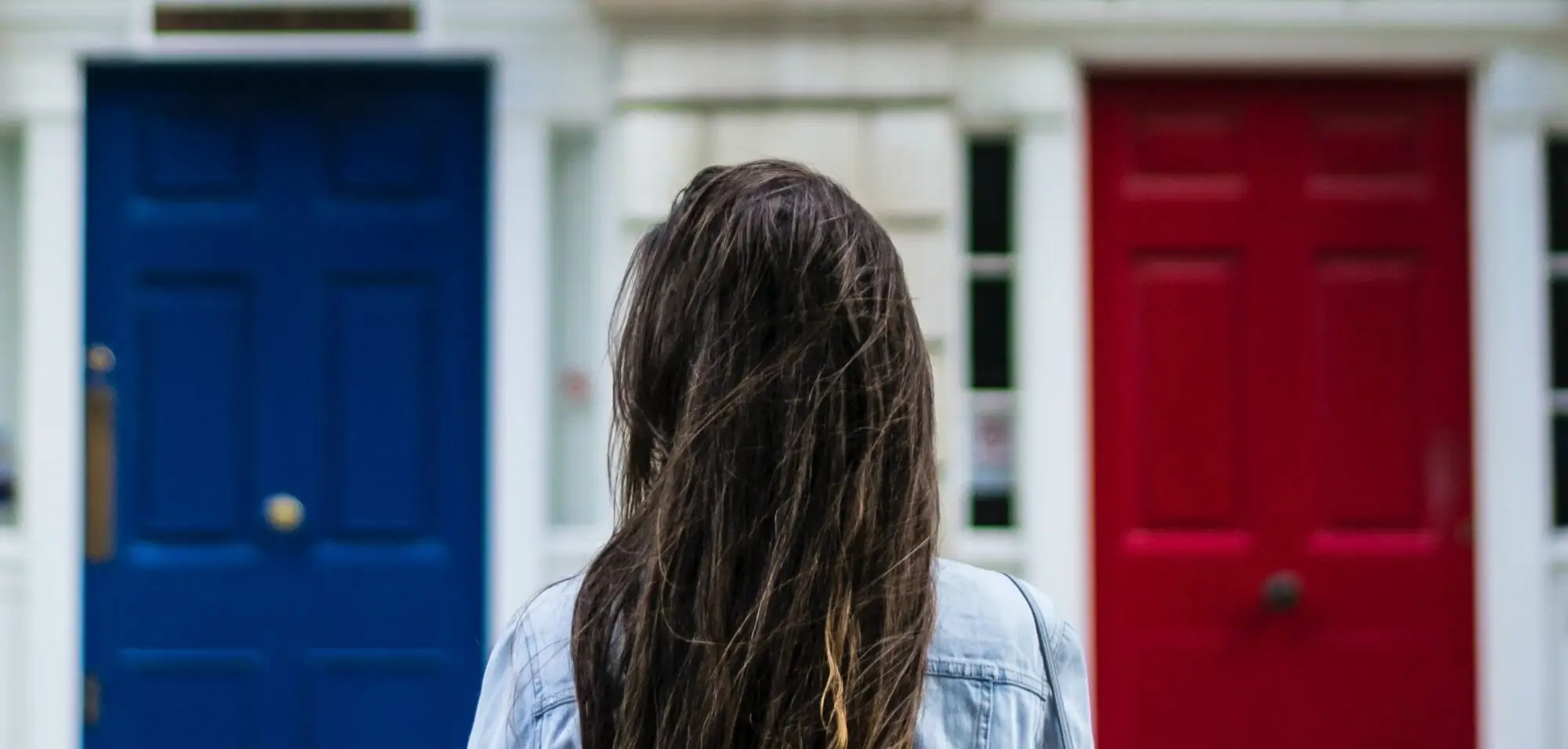 woman in front of blue and red front doors